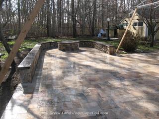 Travertine stone patio with veneered stone sitting wall and fire pit.